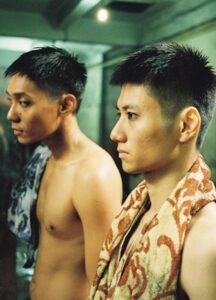 Two Asian men are shirtless, standing next to each other