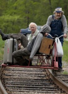 Two old men operate a bike on train tracks