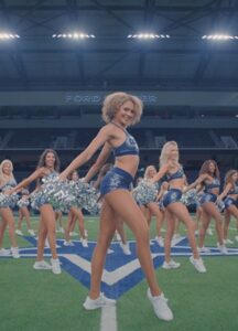 A light skinned Black woman heads a cheer leading dance team.