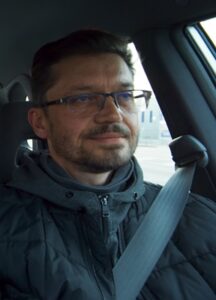 A man in a car is wearing a black coat