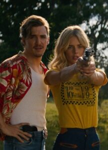 A man, a woman, and a gun in front of trees
