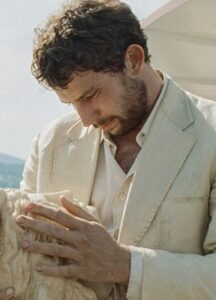 A white man holds a sculpture