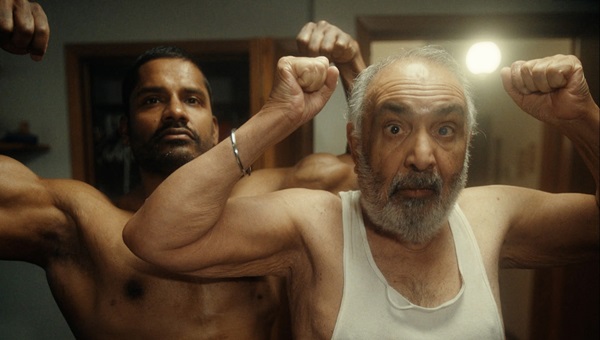 Two men flex in front of the camera